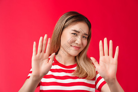 不谢谢素材不 谢谢 我通过了 不情愿的懒惰可爱的亚洲现代女孩展示手挡住拒绝手势 不高兴地笑着摇头 没有情绪 不愿意参与 表现出拒绝 站在红背景