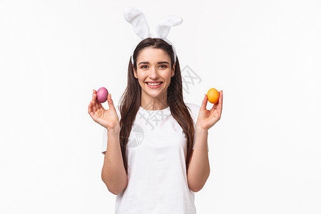 兔耳中可爱的白人女性画像 展示两个彩蛋并微笑 祝贺大家复活节快乐 庆祝和玩乐 白色背景 快乐的 青年幸福高清图片素材