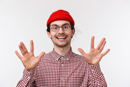 特写肖像滑稽的嬉皮士 戴着红色的帽子和眼镜 用手指和微笑做手势 与朋友极客讨论最喜欢的电视剧 站在白色背景上乐观发型高清图片素材