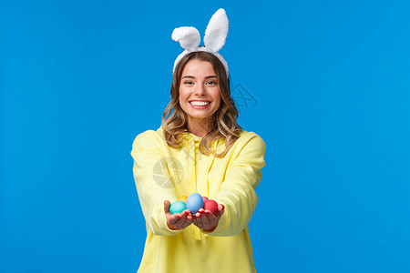 假期 人和有趣的概念 魅力四射的可爱金发女孩拿着彩色复活节彩蛋 戴着兔耳朵 开心地微笑 祝贺家人度过圣日 蓝色背景 大学 学生兔子高清图片素材