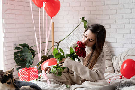 年轻美女坐在床上 庆祝情人节 盛着红玫瑰的晚礼日 花背景图片