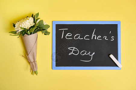 教师节文字一束美丽的秋季紫苑花的平铺组合物 用工艺包装纸绑着绳子和黑板 黄色背景上刻有教师节字样 有文字空间背景