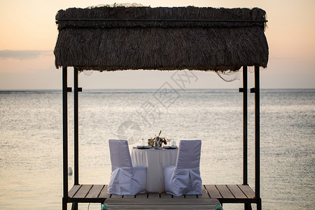 日落时在海滩上开浪漫晚宴 刀 蓝色的 盘子 热带椅子高清图片素材