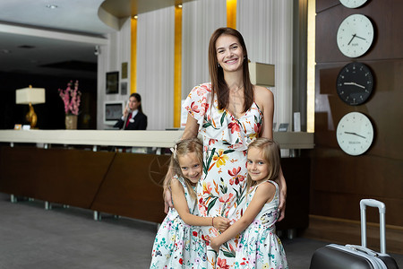 带着双生女儿的母亲在酒店接待处抱抱服务高清图片素材