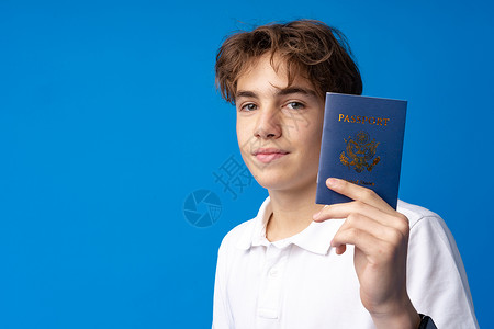 带着蓝色背景放假的护照去度假的喜悦英俊男孩的肖像 身份 脸旅行高清图片素材