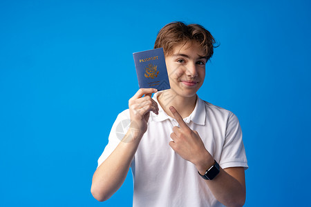 带着蓝色背景放假的护照去度假的喜悦英俊男孩的肖像 脸 男性男生高清图片素材