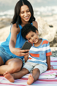留下终生难忘的回忆 拍摄的一位母亲和她的儿子在海滩上自拍图片