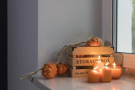 为万圣节准备你的家 一个木制南瓜盒 人造南瓜花环 橙色蜡烛 一杯茶和一个蜡烛灯笼装饰着窗户 咖啡 杯子背景图片