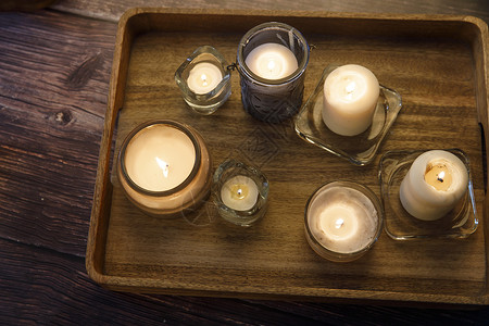 室内和家居舒适概念 顶视景 在桌边的木盘上用玻璃烛台点燃各种大小和形状不同尺寸的蜡烛背景图片