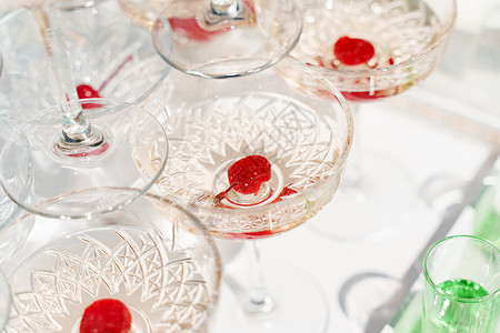 红樱桃在香槟金字塔的葡萄酒杯里 喝着婚礼的餐饮 招待客人的酒精鸡尾酒 开张的商务会议用餐高清图片素材