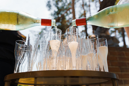 服务员用一次性塑料酒杯倒香槟 将起泡酒倒入森林欢迎饮料区的酒杯中 为商务人士提供餐饮服务庆祝高清图片素材
