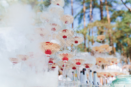 盛装着干冰烟的香槟 里面有闪亮的葡萄酒和红樱桃 为婚礼和商人提供餐饮 液体 玻璃宴会高清图片素材