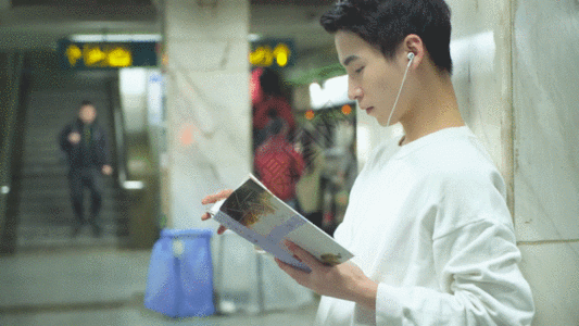 男青年在地铁站着看书GIF图片