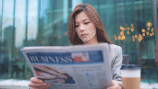 咖啡店背景穿西装的女生坐在咖啡店外看报纸GIF高清图片