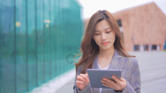 商务女性休闲看书女生拿着平板走在街上GIF高清图片