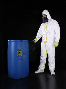 穿防护服的男子检查储存在蓝色容器中的放射物质图片