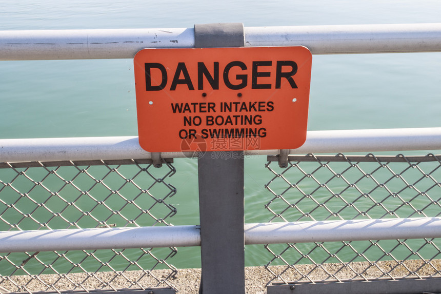 河边栅栏上的橙色警告标志危险水进口不图片
