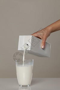手把牛奶从纸箱里倒进玻璃杯里图片