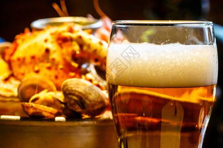 背景的一杯啤酒是一盘螃蟹虾扇贝图片