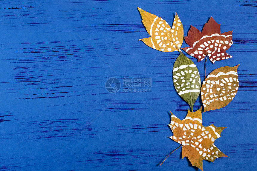 用花边纸巾在干燥的秋叶上手绘儿童艺术项目DIY概念一步的照片说明第4步在蓝色背景上完成涂有复图片
