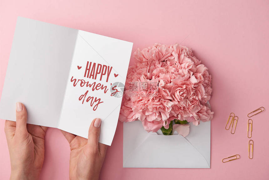 持贺卡的妇女与快乐妇女每天在粉红背景的包里信贴着康乃图片