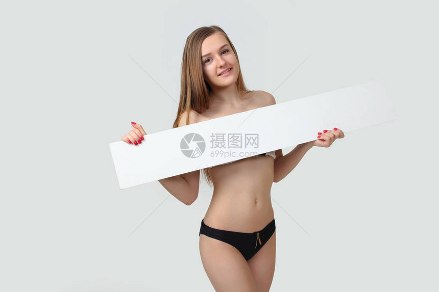 穿着比基尼的感年轻女装扮着空白标牌板图片