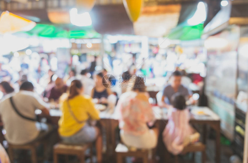 当地亚洲街头食品店在新鲜市场中坐落在桌旁的人抽象形模糊不清图片