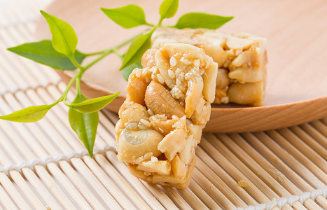 糖果特写一块芝麻花生酥放在小木盘子上面背景