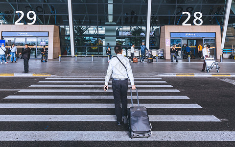 拉着行李走向机场的男子背景图片