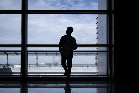 商务人士站在机场落地窗前背景图片