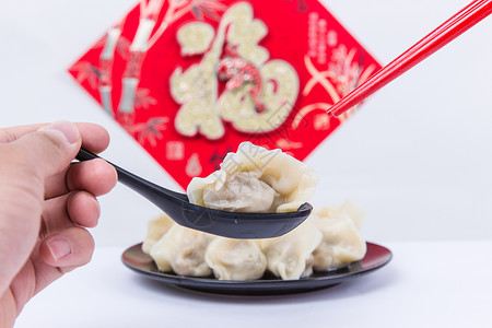 福字为背景的人夹饺子吃的冬至新春节日图片