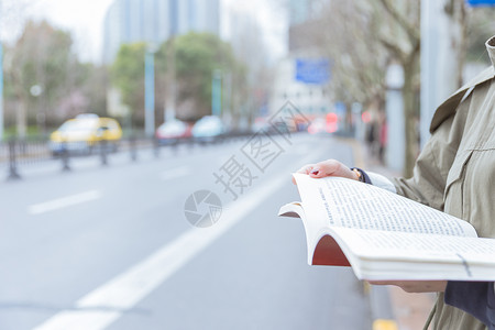 公交亭边等车边看书的女生图片