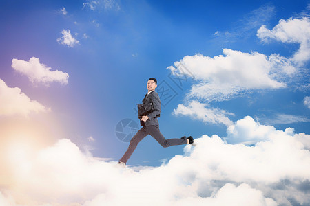 撑伞的男人云朵中跳跃的人设计图片
