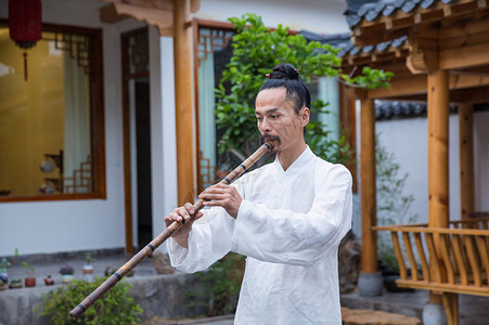 中年养生一位白衣道士在庭院内吹奏长笛背景