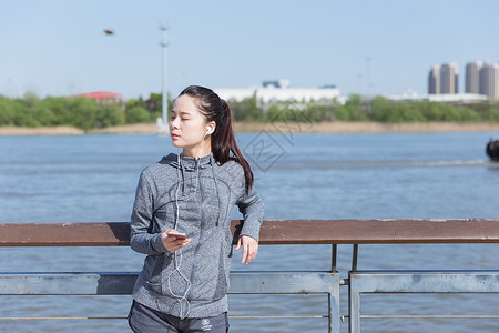 龙与音乐素材运动女孩靠栏杆休息听音乐背景