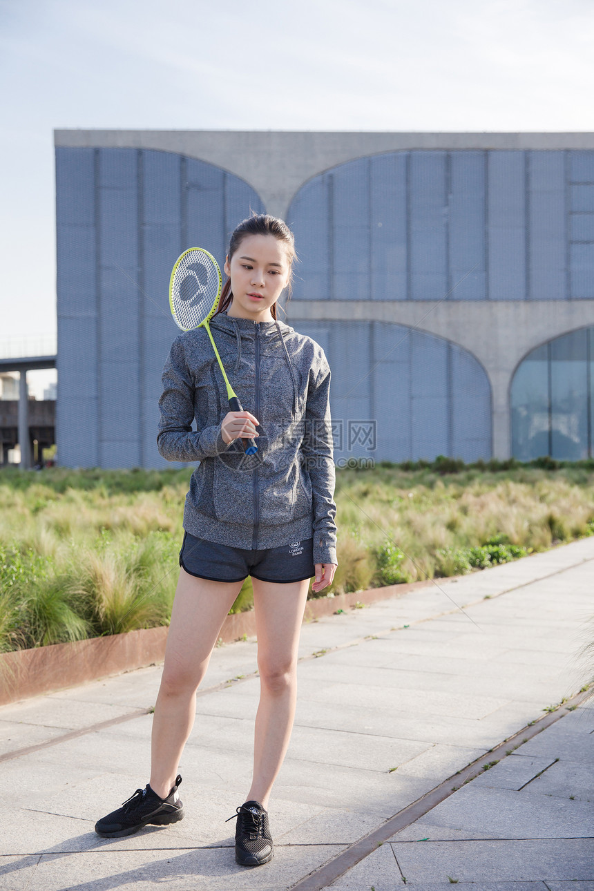 落日运动女孩手拿球拍打羽毛球图片