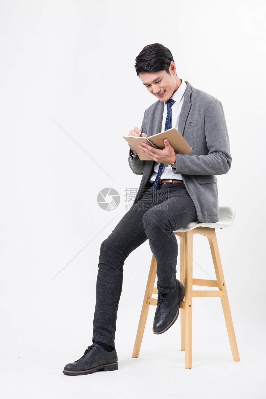 商务男士坐着用笔纸记录书写图片