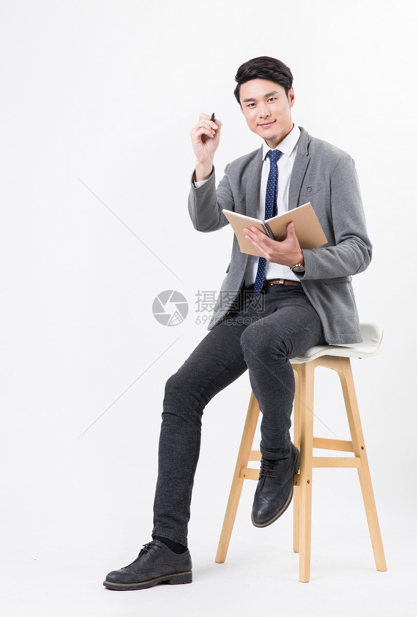 商务男士坐着用笔纸记录书写图片