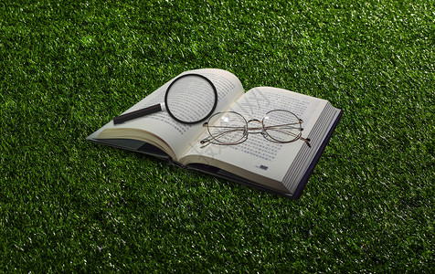 眼镜放在书籍上草地风格放大镜和书设计图片
