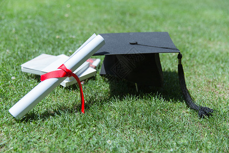 毕业图片大学草地上的书本证书学士帽背景