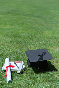 书本和学士帽大学草地上的书本证书学士帽背景