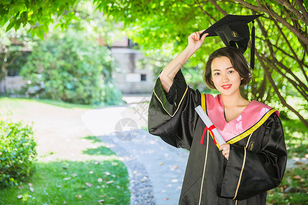 美女拿证书毕业校园树林穿学士服的女学生背景