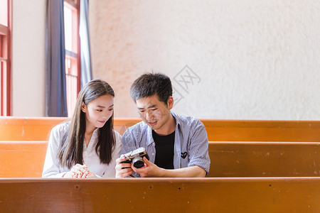 蓝照相机图片男女大学生在教室看相机照片背景