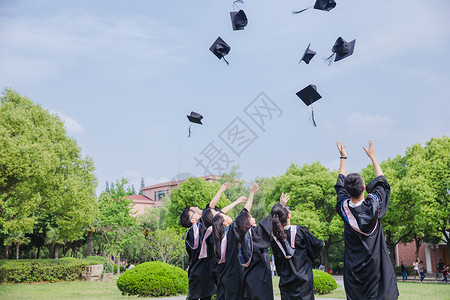 蓝天绿地白云毕业季青春大学生们扔学士帽背景