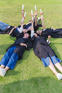 毕业季大学生们躺草地举着证书高清图片