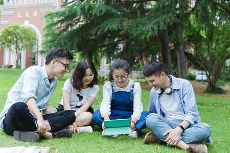 坐男男女大学生们坐草地上聊天休息背景