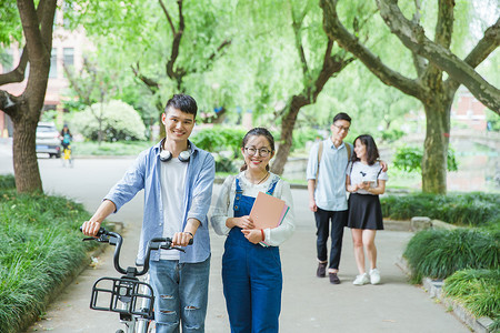 青春大学生推自行车散步聊天高清图片