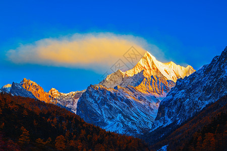 夏诺多吉雪山的日照金山和飘动的云背景图片