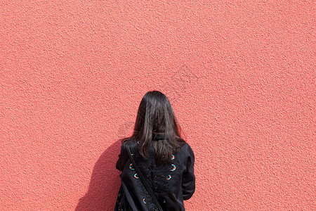 年轻女孩红墙背影留白背景图片