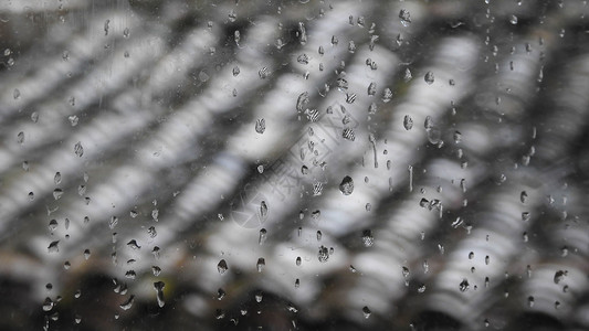 带雨滴的玻璃窗及窗外屋顶高清图片